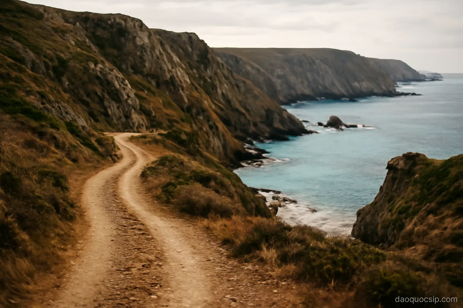 a rugged wild coastline with dirt track winding above steep cliffs and empty turquoise bays