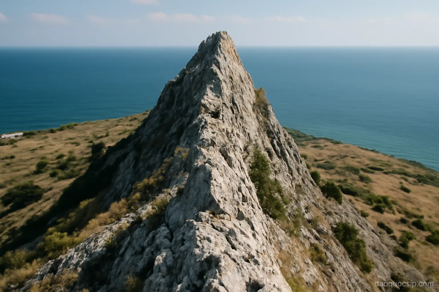 a narrow limestone ridge rising sharply above a coastal plain with the sea beyond