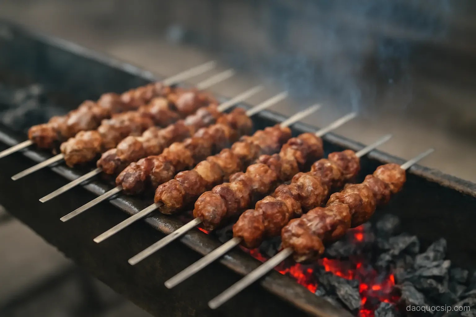 skewers of meat rotating slowly over glowing charcoal in a long narrow grill